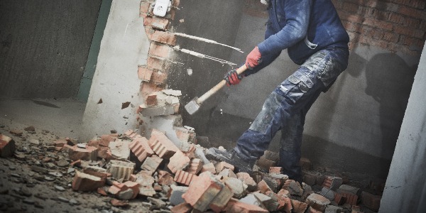 demolition work and rearrangement. worker with sledgehammer destroying wall