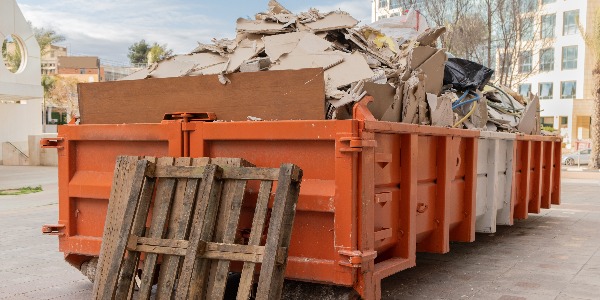 huge heap on metal Big  Overloaded dumpster waste container filled with construction waste, drywall and other rubble near a construction site.